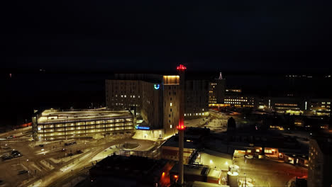 Disparo-De-Un-Dron-Elevándose-Frente-Al-Hospital-Iluminado-De-Vaasa,-Noche-En-Finlandia