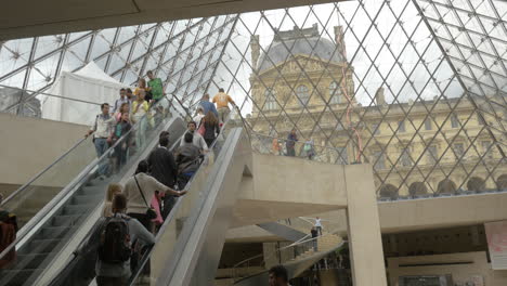 Gente-Montando-Escaleras-Mecánicas-Bajo-Tierra-La-Pirámide-Del-Louvre