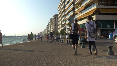 Dos-Jóvenes-Caminan-Por-El-Paseo-Marítimo-De-Tesalónica,-Grecia