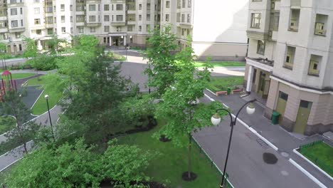 Two-cars-driving-in-the-yard-of-multistorey-houses-aerial-view