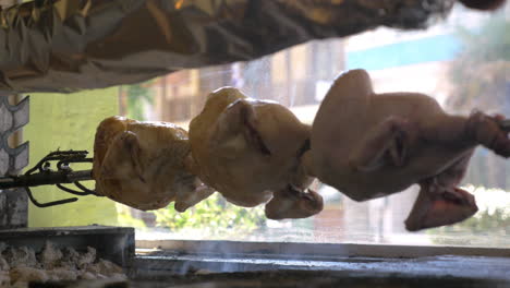 Pollo-A-La-Parrilla-Girando-Sobre-Una-Brocheta-En-La-Cafetería-Contra-La-Ventana-De-Visualización