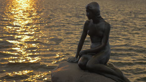 Die-Kleine-Meerjungfrau-Auf-Dem-Wasserhintergrund-Bei-Sonnenuntergang