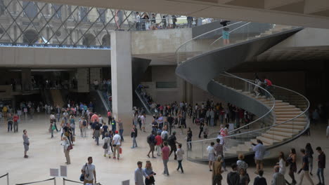 Salón-Lleno-De-Gente-Con-Escaleras-De-Caracol-En-La-Pirámide-Del-Louvre