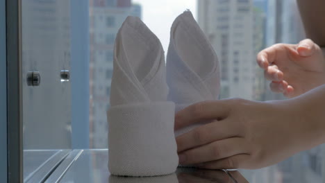 View-of-hands-putting-hotel-towels-in-bathroom-with-city-background