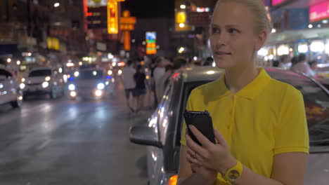 Mujer-Enviando-Mensajes-De-Texto-Al-Celular-Y-Mirando-La-Noche-En-Bangkok,-Tailandia