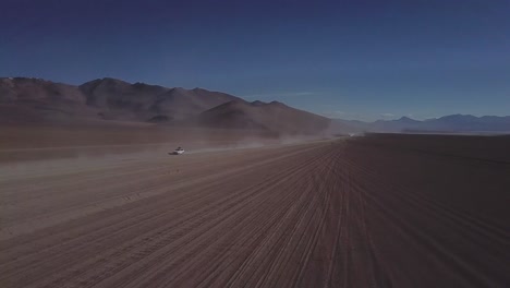 Epic-drone-shot-of-off-road-vehicles-driving-on-desert-dirt-road,-Bolivia-and-Chile-route