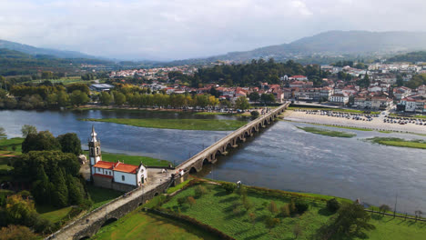 Stunning-aerial-4K-drone-footage-of-a-village---Ponte-de-Lima-in-Portugal-and-its-iconic-landmark---Stone-roman-bridge-crossing-over-the-Lima-River