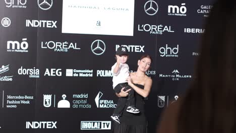 Familia-De-La-Semana-De-La-Moda:-Modelo-Eleva-A-Su-Hijo-En-Madrid,-Logotipos-De-Mercedes-Y-L&#39;oreal