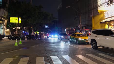 Fußgängerzone-Während-Der-Hauptverkehrszeit-In-Der-Nacht,-Weißes-Auto,-Das-Nach-Links-Abbiegt,-Dann-Menschen,-Die-Nicht-Auf-Den-Weißen-Linien-überqueren,-Bangkok,-Thailand