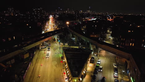 Aerial-view-of-a-train-crossing-rails-above-the-night-lit-streets-of-Chicago