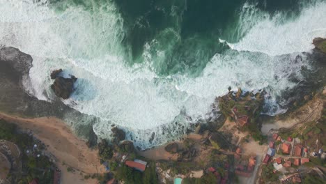 Aerial-top-down-view-of-ocean-wave-crashing-onto-tropical-beach