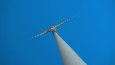 Low-dutch-angle-view-of-wind-turbine-with-clear-blue-sky-on-the-background