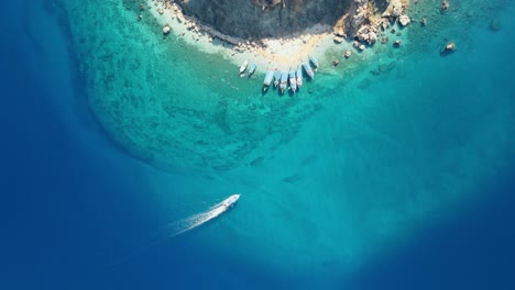Aerial-top-down-4K-drone-view-of-a-boat-riding-to-Suluada-Island-in-Adrasan-Sea,-Antalya-–-Turkey