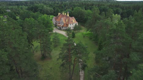 Drone-fly's-away-from-mansion-in-forest-between-pine-trees,-good-place-for-getaway