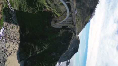 Young-woman-overlooks-the-ocean-and-a-bridge-from-the-edge-of-a-cliff