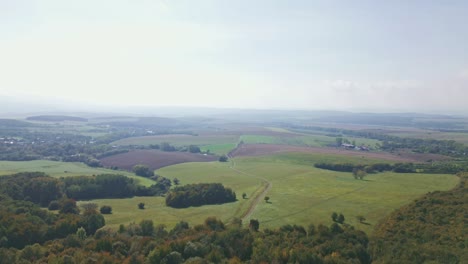 Flug-über-Wald-Und-Wiesen-Mit-Blick-Auf-Die-Agrarlandschaft-Im-Hintergrund