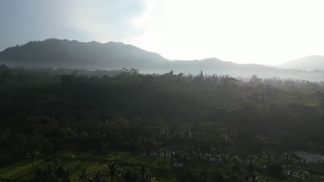 Sunrise-over-jungle-trees-and-mountains-in-the-East-of-Bali,-aerial