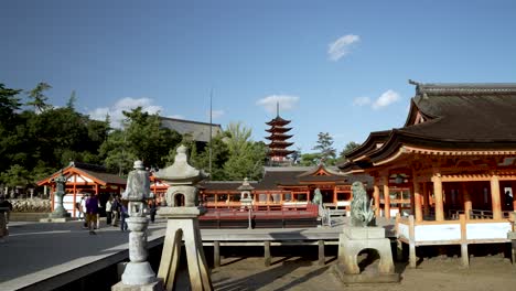 Itsukushima-Shrine-on-Miyajima-Island,-tourists-walking-around-on-a-sunny-day