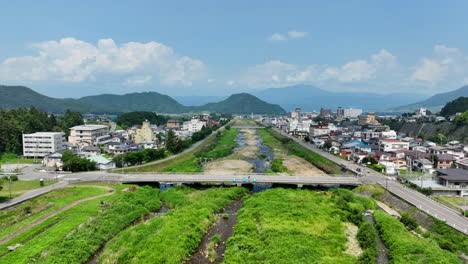 Aerial-view-rising-over-the-Yomase-river-in-Yamanochi,-sunny,-summer-day-in-Japan