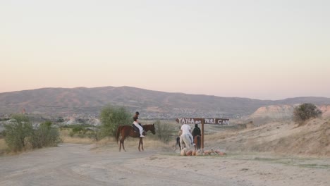 Group-horseback-riders-follow-marked-trail-golden-hour-landscape