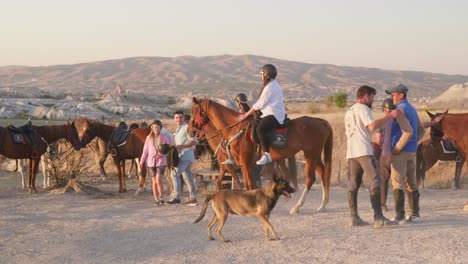 Dogs-follow-sunset-guided-horseback-tourist-group-Cappadocia-landscape