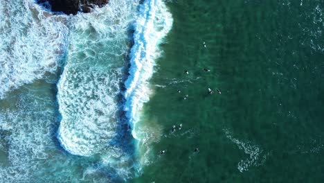 Drone-aerial-shot-of-sand-bar-ocean-waves-floor-surfers-paddle-white-wash-riding-surfing-waiting-in-line-up-ocean-beach-Kiama-surf-Gerringong-South-Coast-travel-tourism-NSW-Australia-4K