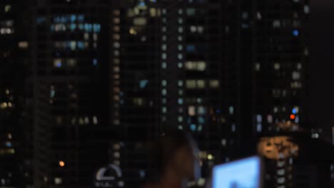 View-of-woman-taking-notes-in-tablet-in-the-swimming-pool-on-the-skyscraper-roof-and-night-city-landscape-Kuala-Lumpur-Malaysia