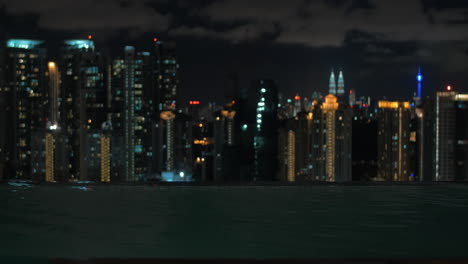 Vista-De-Una-Mujer-Nadando-En-La-Piscina-En-El-Techo-Del-Rascacielos-Contra-El-Paisaje-Nocturno-De-La-Ciudad-Kuala-Lumpur-Malasia