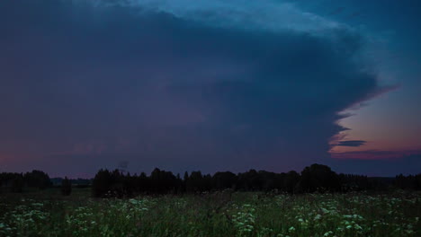 Lightning-storm-clouds-flash-light-on-dark-grey-day-above-flower-meadow-by-forest