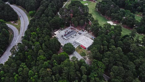 Aerial-flyover-forest,-highway-with-traffic,-golf-course-and-buildings-in-Stone-Mountain,-GA