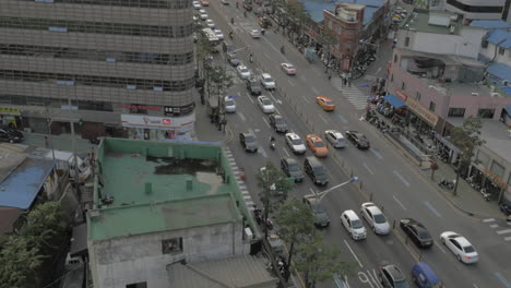 Seen-busy-road-with-passing-cars-buses-motorcyclists-and-walking-people-towering-skyscrapers-buildings