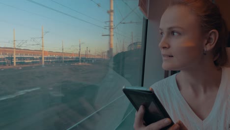 In-Saint-Petersburg-Russia-in-train-rides-young-girl-and-looking-out-the-window-holding-a-cell-phone