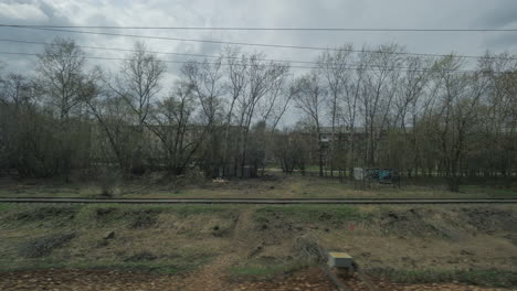 View-from-the-window-of-a-moving-train-seen-trees-buildings-bridges-and-railroad