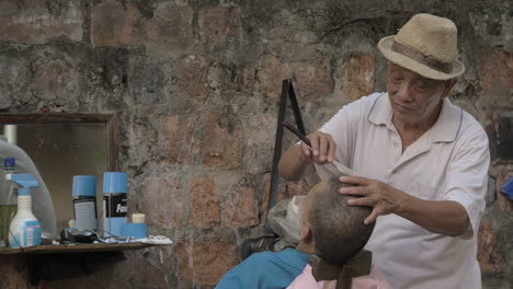 Senior-man-shaving-another-man-by-old-blade-traditional-haircut