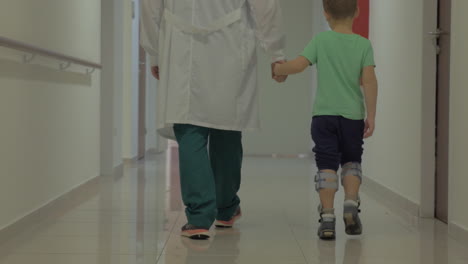 Niño-Y-Médico-Caminando-Por-El-Pasillo-Del-Hospital.