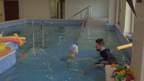 Therapeut-Trainiert-Mit-Einem-Kind-Im-Pool