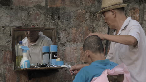 Senior-street-Barber-cuts-a-man-with-a-straight-razor-while-a-man-looks-in-the-mirror