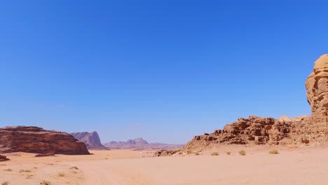 Barren-sandy-sandstone-desert-landscape-under-clear-blue-sky,-Wadi-Rum