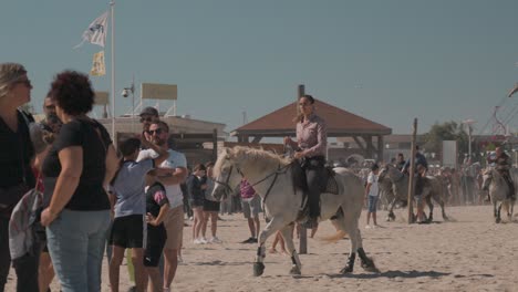 Hermosa-Mujer-Ordena-Con-Gracia-El-Caballo-De-Camargue-En-La-Playa-En-Feria-Palavas