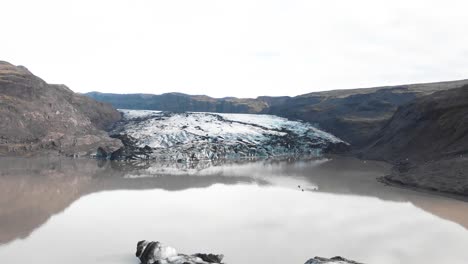 People-kayaking-in-muddy-Solheimajokull-glacier-lake-moraine,-Iceland