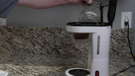 -A-man-pours-water-into-a-coffee-maker-to-be-brewed