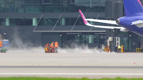 Ground-crew-using-high-pressure-air-on-a-runway-near-parked-planes