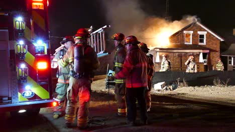 Team-of-firefighters-training-to-extinguish-a-house-fire-at-night