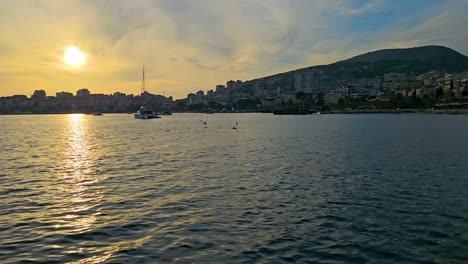 Saranda-Sunset-Timelapse:-Coastal-City's-Bay-Transforms-Under-the-Golden-Glow,-Revealing-the-Tranquil-Beauty-of-Ships-in-Port