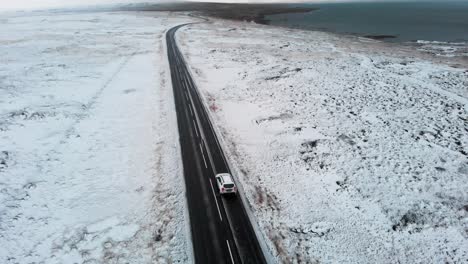 SUV-Conduciendo-Por-Una-Carretera-Asfaltada-En-Un-Paisaje-Invernal-De-Hielo-Nevado,-Islandia