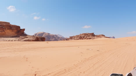 View-from-above-caravan-desert-tour-car-driving-across-open-sand-desert-of-Wadi-Rum