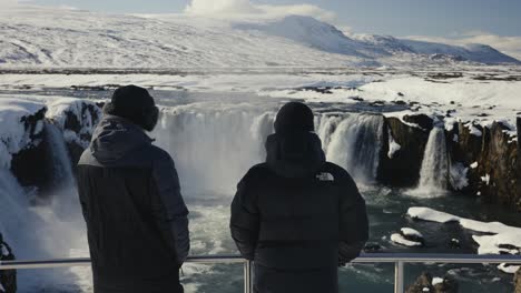 Father-and-son-enjoy-scenic-Godafoss-waterfall-during-sunny-winter-day