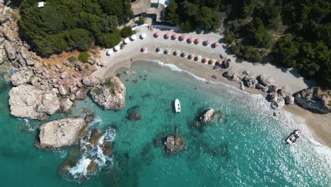 Drone-top-down-bird's-eye-view-of-skiff-anchored-at-entrance-to-luxury-beach-bay