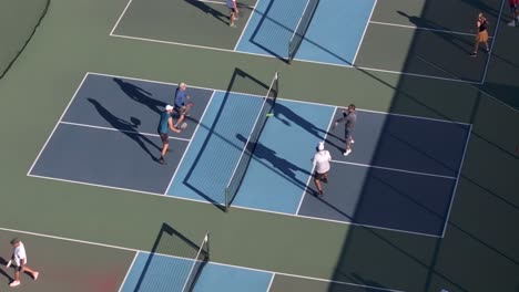 Amateur-players-playing-a-game-of-Pickleball,-rally-for-winning-point-on-blue-court-,-aerial-static-view