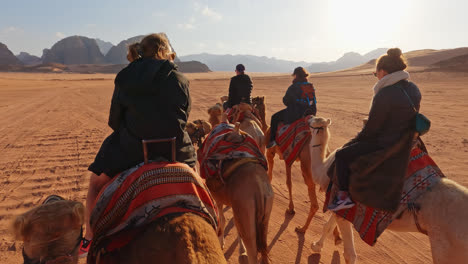 Tourists-gather-together-riding-on-pack-of-camels-in-Wadi-rum